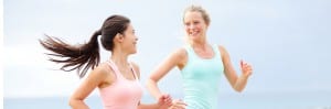 two woman on a jog looking at each other smiling