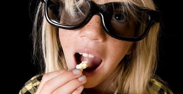 woman wearing 3d glasses eating popcorn