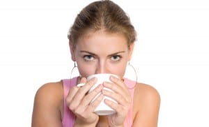 woman staring at camera while drinking from mug